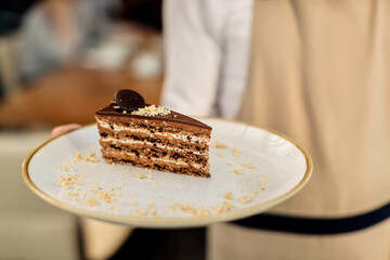 Close-up of waiter serving chocolate cake in a cafe,