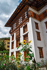 Fototapeta na wymiar A traditional bhutanese building surrounded by sunflowers, in Thimphu, capital of Bhutan.