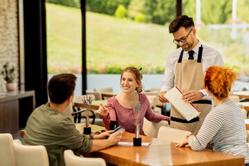 Group of happy friends talking while making order in a cafe.