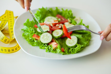 Diet food, closeup of fresh salad in a bowl and yellow measure tape