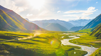 Fototapeta na wymiar Truck is driving through truso valley with terek river on the right side surounded by KAzbegi mountains. Scenic georgian highlands during the sunset.
