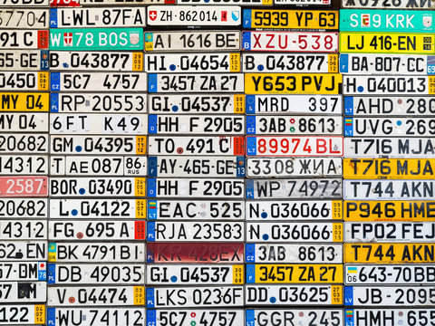 Odessa, Ukraine - Circa 2017: License Numbers Auto From All Over World On Display. Discontinued License Plate Of Cars From Europe Car On Old Wall. Background Of Old Vintage Antique Car License Plates 