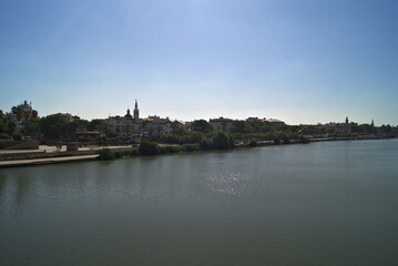 Fototapeta na wymiar Vistas del río Guadalquivir a su paso por el Muelle la Sal y de la avenida Paseo Colón en Sevilla desde el puente de Triana (Andalucía, España).