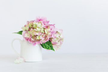 Romantic bouquet of pink Hydrangea flowers in a jar on a white background.