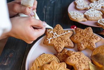 Boy is decorating  gingerbread cookies with icing sugar. Snowflake, star  shapes. 