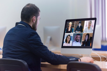 Group Using Video Conferencing technology in office for video call with colleagues abroad during coronavirus quarantine.