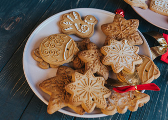 Homemade christmas gingerbread cookies on plate on wooden background. Snowflake, star, tree, snowman, deer shapes. Holiday, celebration and cooking concept. New Year and Christmas postcard, close up.