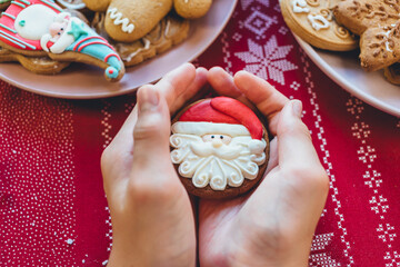 Boy is holding gingerbread cookies with icing sugar. Christmas gift gingerbread on wooden dark table. Holiday, celebration and cooking concept. New Year postcard. Close up