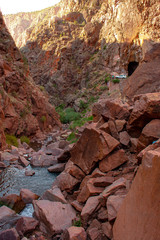 Mountain stream flows through red rock desert canyon with road and tunnels in background, located in Gilman Tunnels, Jemez Mountains, New Mexico, USA