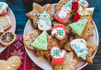 Homemade christmas gingerbread cookies on plate on wooden background. Snowflake, star, tree, snowman, deer shapes. Holiday, celebration and cooking concept. New Year and Christmas postcard, close up.	