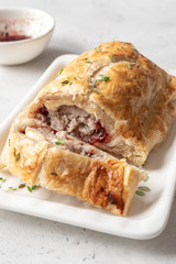 Baked pork sausage rolls with brie cheese and cranberry sauce in puff pastry