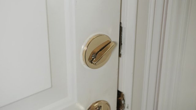 Man locking deadbolt door lock on white entry door. Home security burglar and robbery prevention.