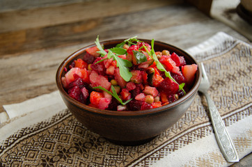 Vegetable salad, vinaigrette, in a ceramic earthenware, a folkloric bowl with a kitchen napkin on a wooden table. Village life. Home cooking.