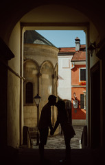 Silhouette of young couple kissing each other under the arch. 