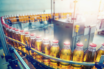 Juice in bottles on beverage plant or factory on conveyor belt, industrial production line.