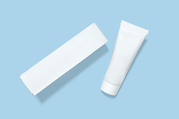 Face cream mockup. Top view of plastic cosmetic tube with packaging box on blue. Blank Template. Flat Lay.