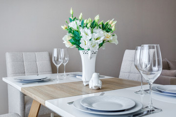 served table with a bouquet of roses in interior of modern luxure guest room in studio apartments in minimalistic style