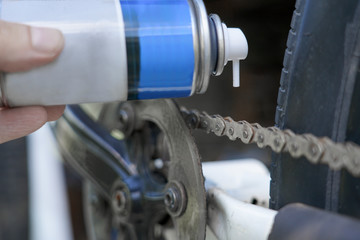 hand holding spray lubricant in his hand to lubricate the bike chain
