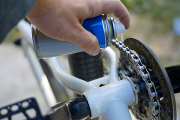 hand holding spray lubricant in his hand to lubricate the bike chain