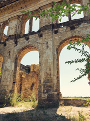 Naklejka premium Mystical Interior, ruins of facade of an abandoned ruined building of an ancient castle 18th century. Old ruined walls, corridor with garbage and mud. Ruins Ancient historic building destroyed by war