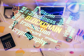 Blockchain theme hologram drawings over computer on the desktop background. Top view. Multi...
