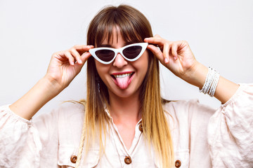 Naklejka premium Crazy funny portrait of woman showing long tongue, making grimace, summer trendy look.