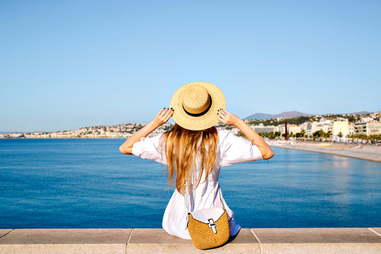 Touristic picture of happy elegant woman posing back, put her hand in the air and enjoying amazing view in France Cannes beach, traveling goals, elegant glamour clothes, summertime.
