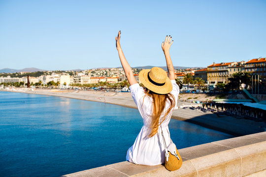 Touristic picture of happy elegant woman posing back, put her hand in the air and enjoying amazing view in France Cannes beach, traveling goals, elegant glamour clothes, summertime.