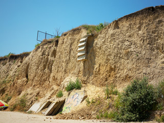 Сoncrete staircase collapsed in a landslide of soil after heavy rains on the coast of the Black sea. Destruction of the coast as a consequence of soil erosion. Landslide - threat to life.