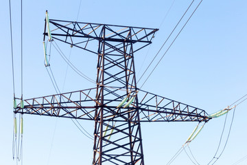 Power lines. High voltage power pylons against blue sky and sun rays