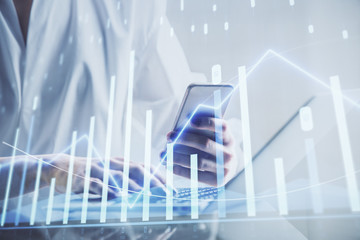 Double exposure of financial graph sketch hologram and woman holding and using a mobile device. Stock exchange concept.
