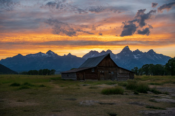 Fototapeta na wymiar The first moulton barn on Mormon Row in Moose, Wyoming - Grand Teton National Park. This is one of the most photographed barns in the country. Photo taken during sunset showing vivid orange colors.