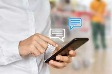 Man hand using mobile phone typing, with chat icons. Social media and technology concept.