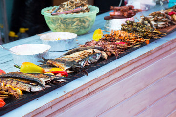 Various seafood on the shelves of the fish market. Marinated fried mussels, shrimp, octopus, conch shell, grilled fish cooked over a fire on the street. Street trade.