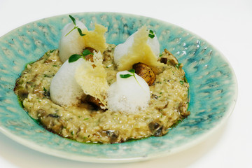 creamy mushroom risotto, Italian rice speciality with crispy parmeesan cheese, foam and herbs