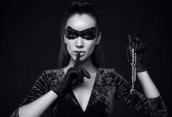 Elegant brunette woman in beautiful purple dress, sequins mask and black gloves