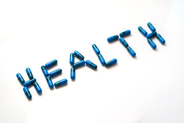 blue pills forming the word health on a white background, tilted view