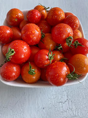 Cherry tomatoes with water droplets on a white crackle surface 