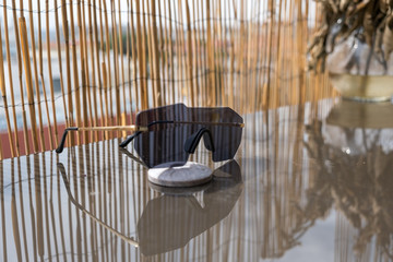 Futuristic sunglasses rimless design with black lens on a table with bamboo fence background. Selective Focus 