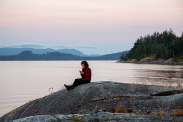 Girl Watching a Peaceful Sunrise on the Ocean Coast during Sunny Summer. Taken in Saltery Bay, Sunshine Coast, British Columbia, Canada.