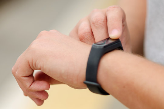 Young man checks swf fitness bracelet. The watch is on the left hand