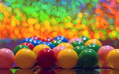 close up of round bubble gums on a mirror on a multicolored bokeh background