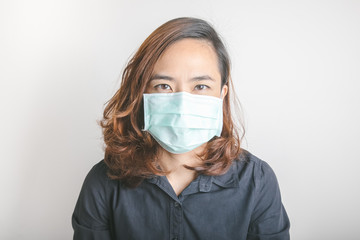 Close up face shot of pretty asian woman model with age of 30s who is wearing medical mask to protect virus and influenza epidemic shows strong and beauty eye contact on white background in studio