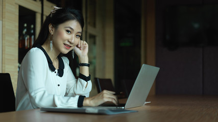 Portrait of female office worker working with laptop on meeting table