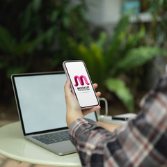 Female working with mock up smartphone and laptop on coffee table in garden
