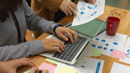 Side view of office workers working with paperwork, laptop and mock up tablet on meeting table