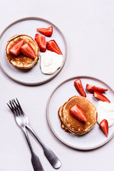 Homemade pancakes with strawberry and whipped cream (chantilly) on grey concrete background. Selective focus