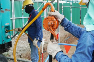 Workers use rotate the hand pump for sucking oil to fuel up the electricity generator.