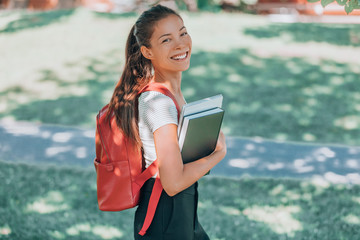 Happy university student. Asian young woman smiling at camera, walking on campus with backpack, laptop, book. Back to school concept.