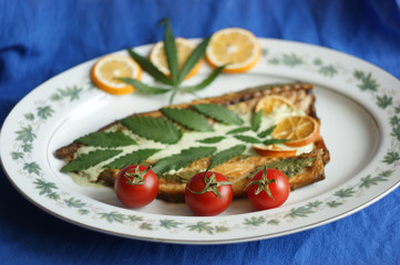 three red tomatoes on a background of fish food with cannabis. blurred cannabis leaves on background